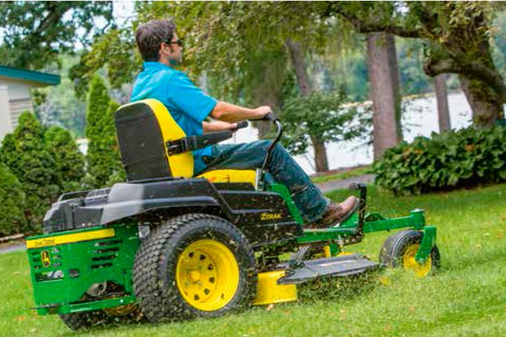 ztrac spakstyr gressklipper fra john deere kjører igjennom hagen med en mann i blå skjorte ved spakene