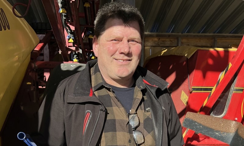 Mann med kanne bladgjødsel foran åkersprøyte