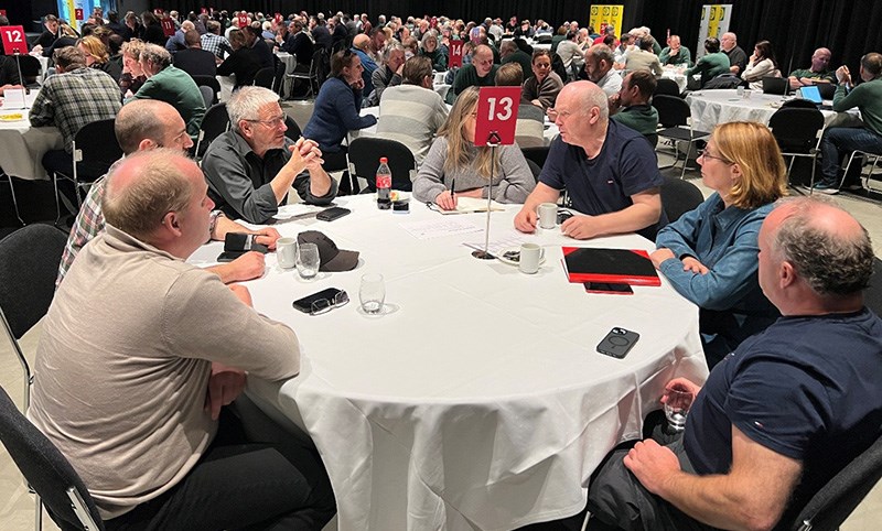 Mennesker samlet rundt runde bord i konferansesal