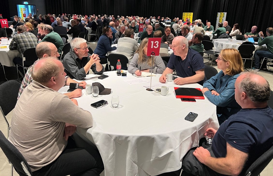 Mennesker samlet rundt runde bord i konferansesal