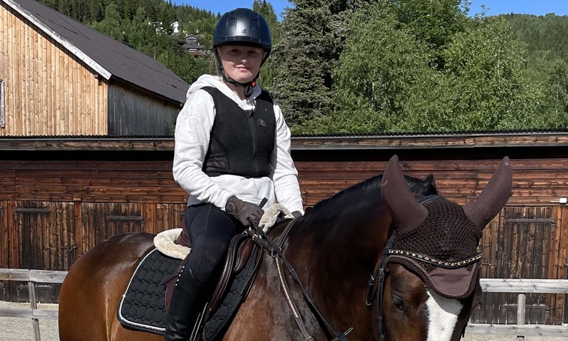 Jente med rideutstyr på hest