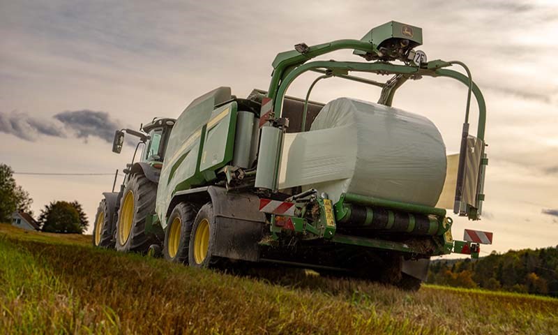 John Deere traktor med rundballepresse i aksjon på jordet