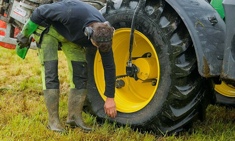Mann sjekker lufttrykket på hulet til John Deere traktor