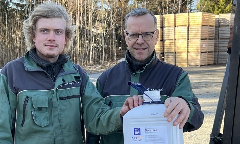 To menn med en kanne plantevernmiddel foran potetkasser