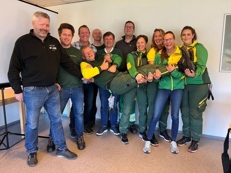 Stor gruppe folk løfter en mann