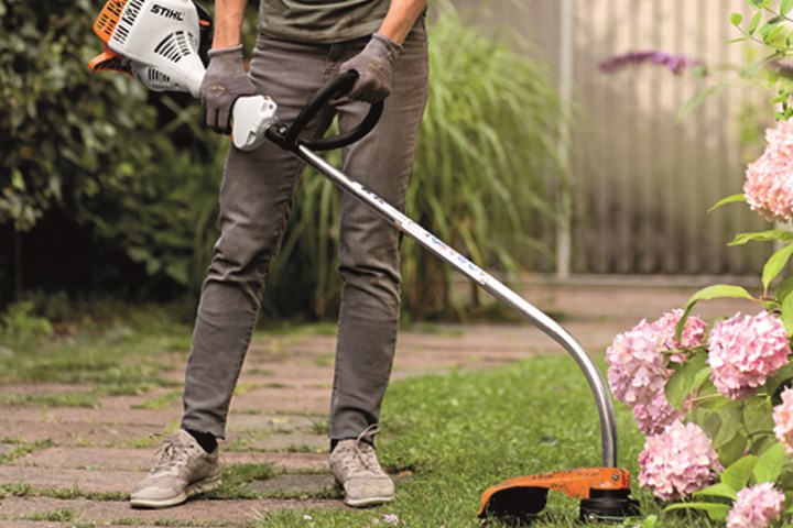 Person som bruker gresstrimmer i hagen