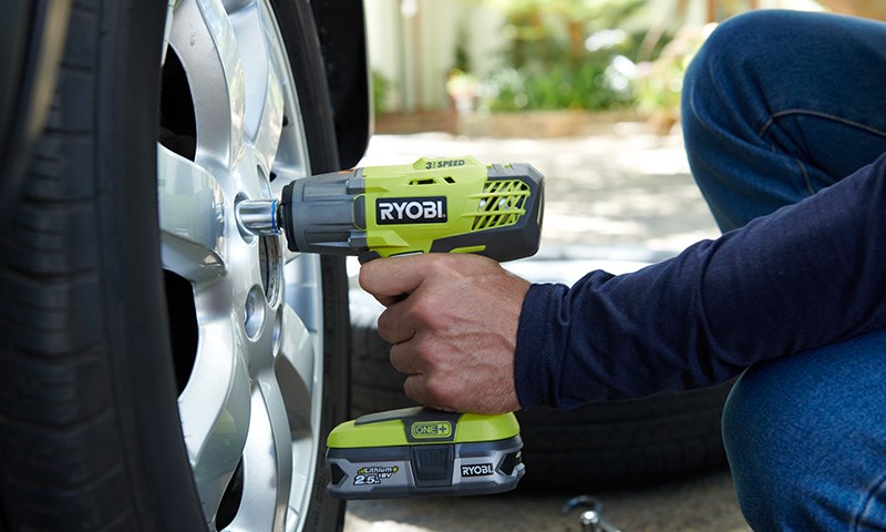 En hånd som løsner muttere på dekk med en Ryobi muttertrekker