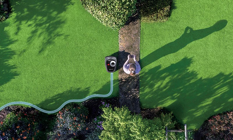 Person går med en Segway robotgressklipper,, legger inn klippeområde i app