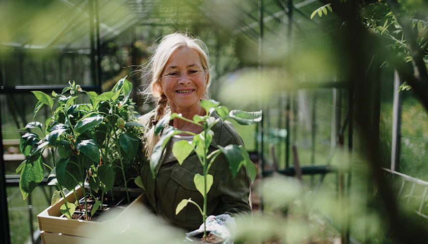 Dame i drivhus med grønne omgivelser