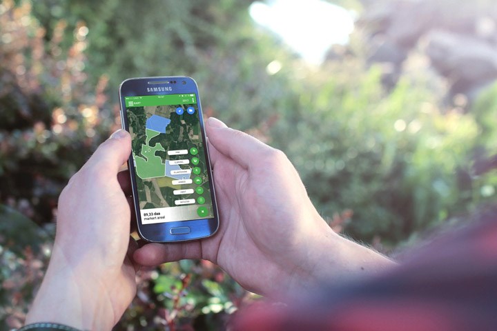Hender som holder en telefon med CropPLAN på skjermen
